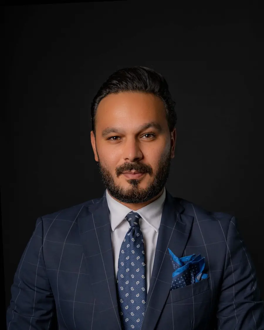 Studio portrait of Ayoub in a navy suit